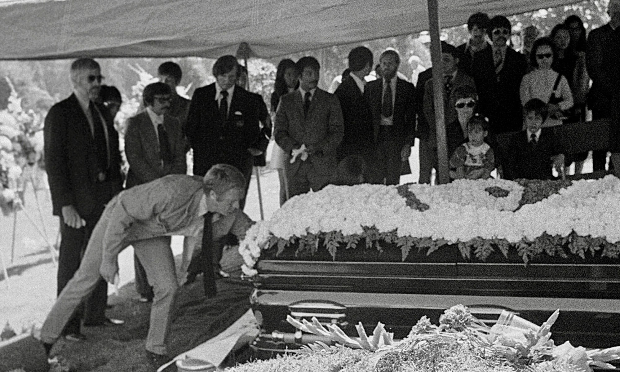 Steve McQueen places his gloves on Bruces casket James Coburn on the left - photo 5