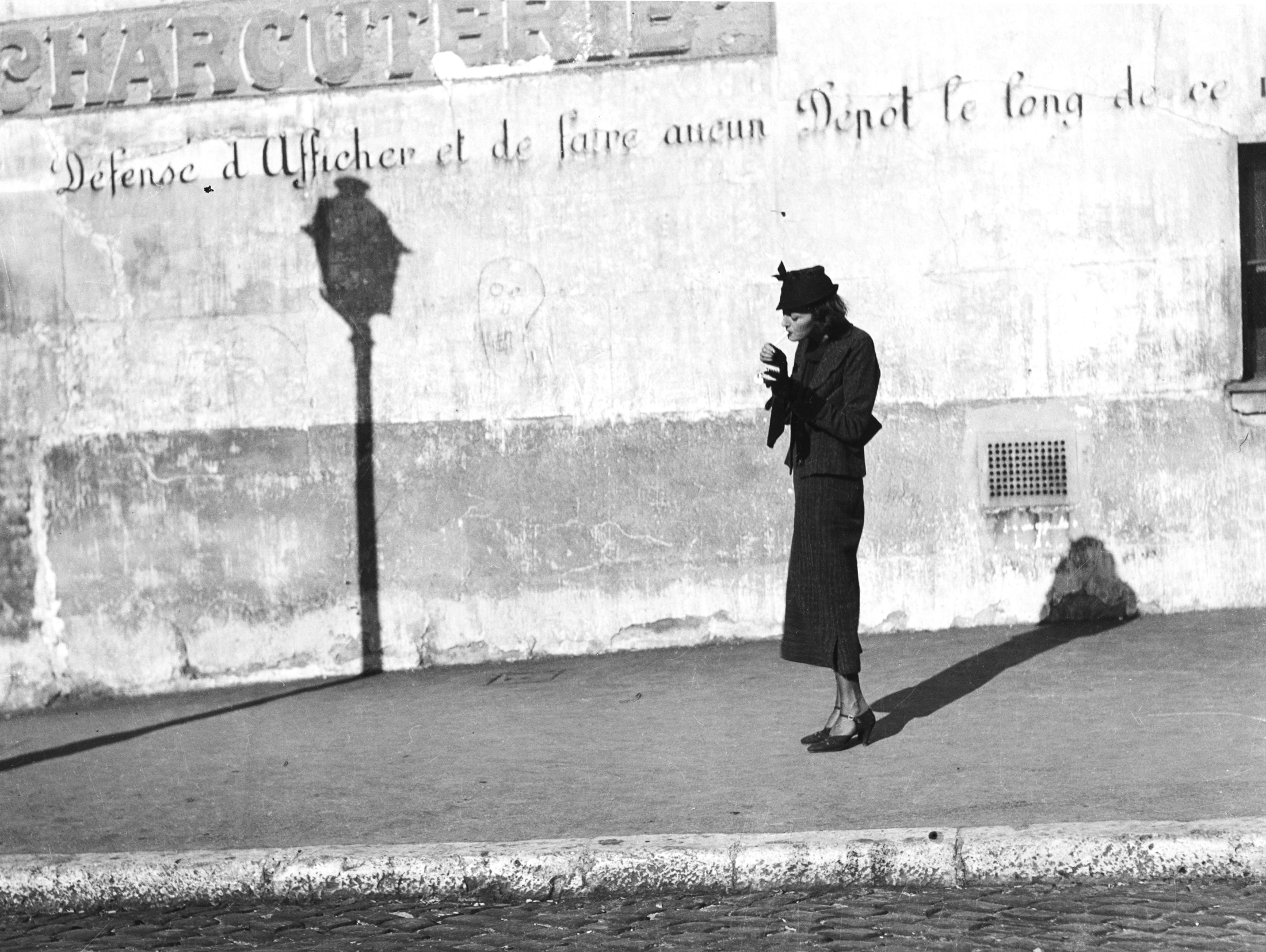 On a street in Paris a woman pauses to light a cigarette She holds up a match - photo 3