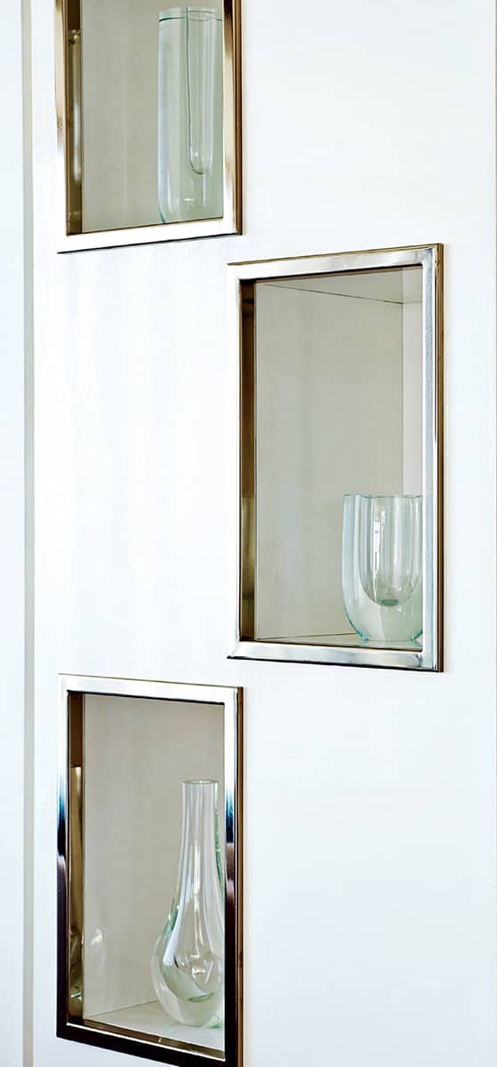 A collection of glass vessels is displayed in chrome-framed niches built into - photo 4