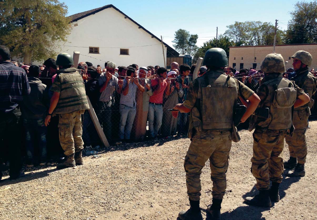 Turkish soldiers hold back Syrian Kurds who are trying to cross the border into - photo 11