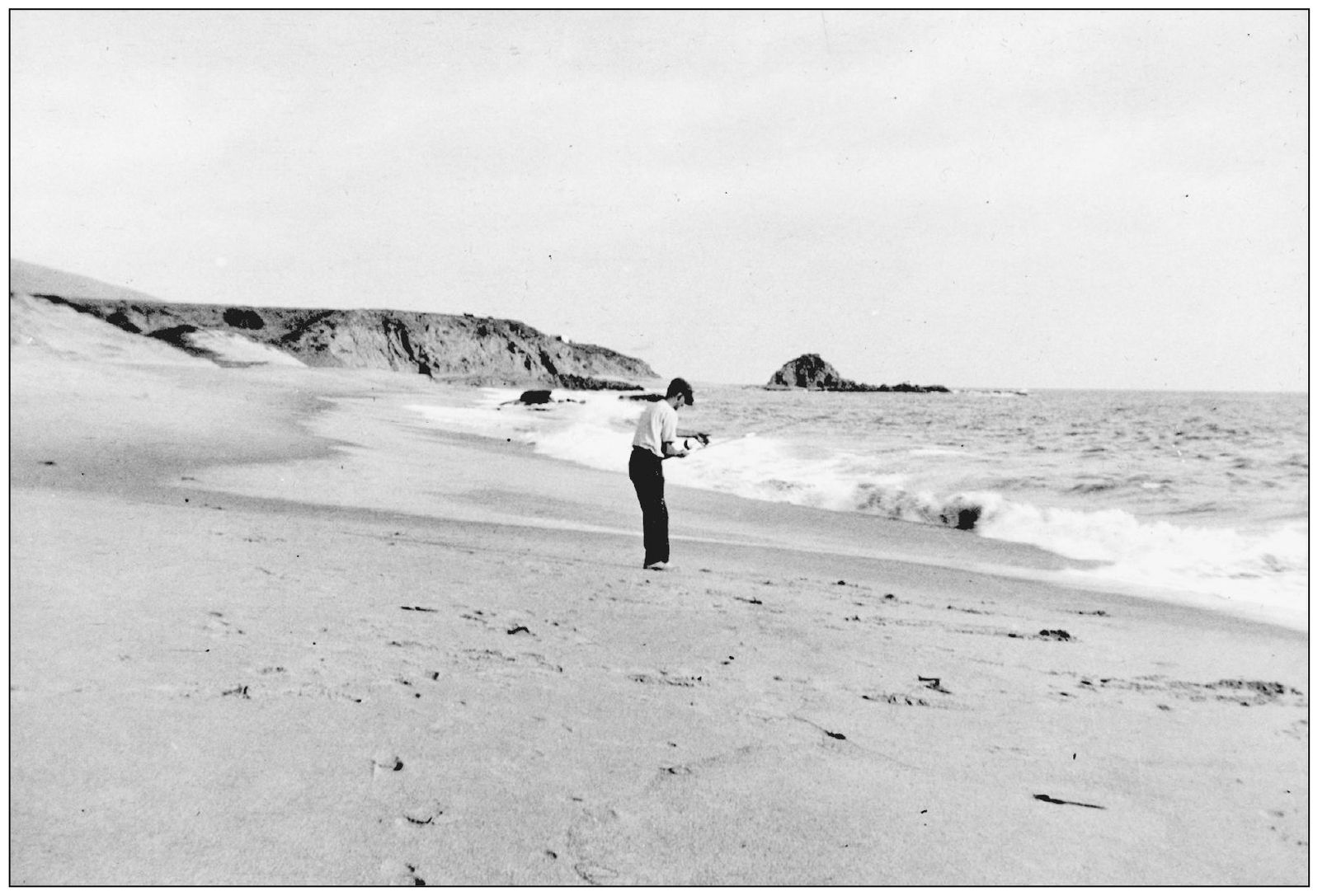 A lone fisherman stands on Victoria Beach with Goff Island in the background - photo 4