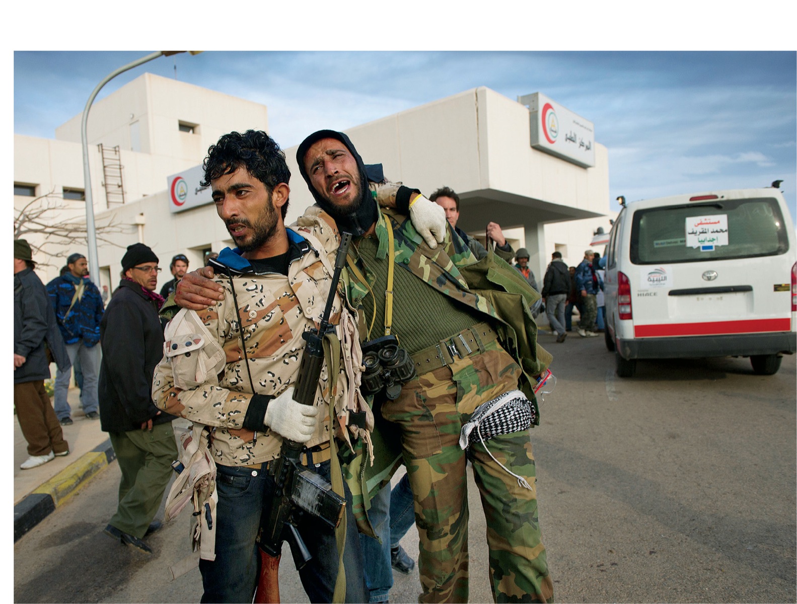 A rebel fighter consoles his wounded comrade outside the hospital in Ras Lanuf - photo 7