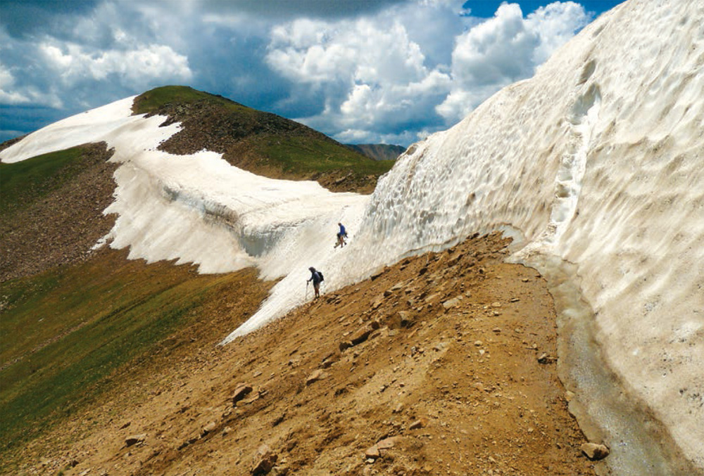 Hikers scoot down the remains of snow cornices at the top of Jones Pass - photo 9