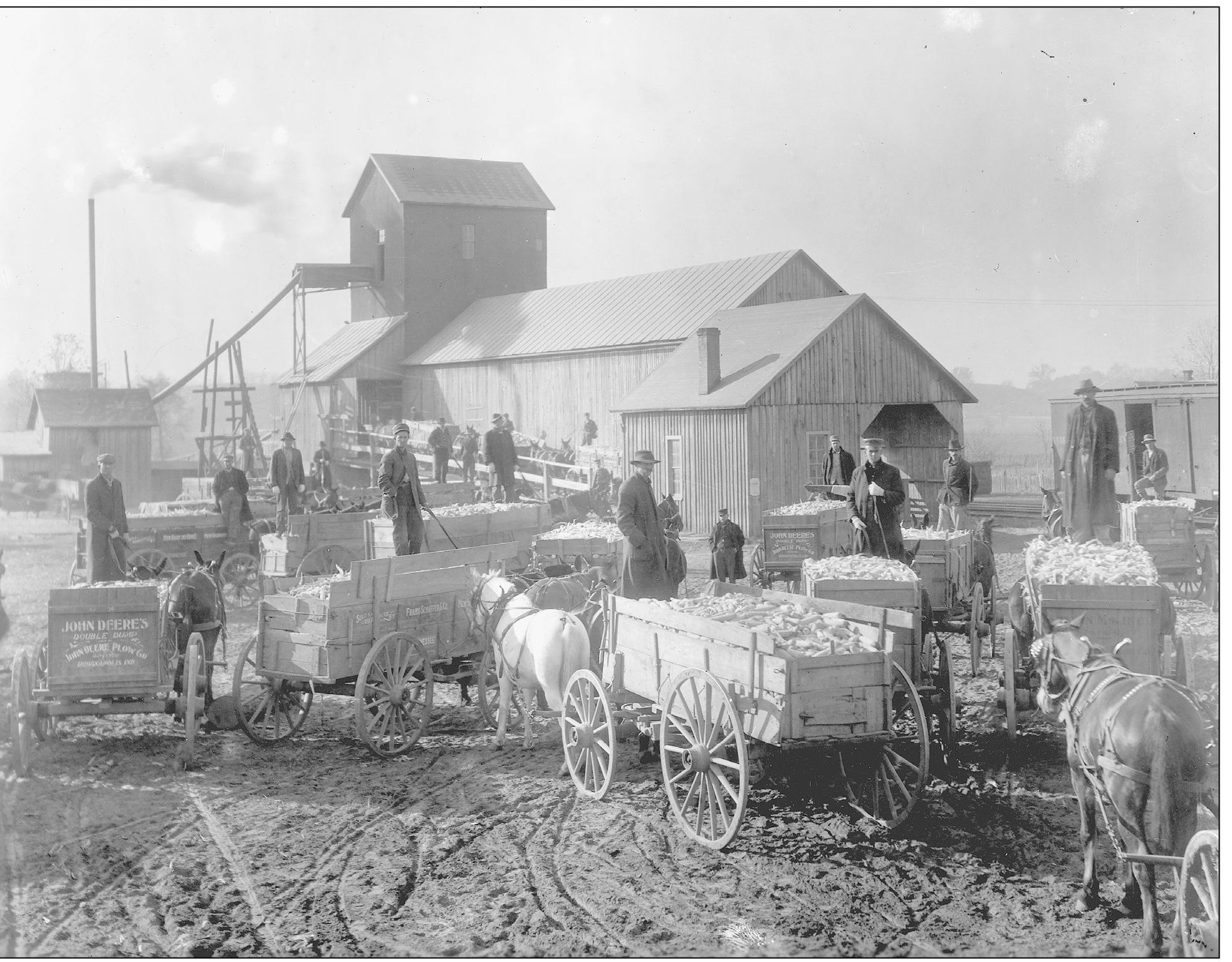 Horse-drawn wagons full of corn gather around the lot at the grain elevator - photo 7