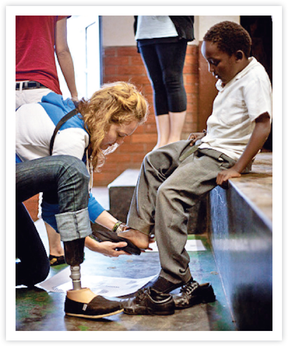 Putting shoes on the feet of South African children during the TomsElement - photo 19