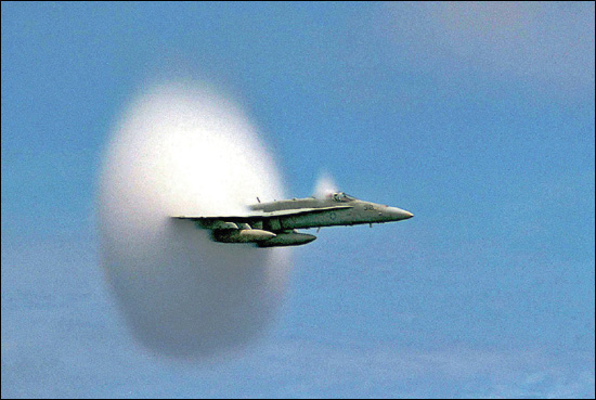 An FA-18 Hornet breaking through the sound barrier in low level flight above - photo 4