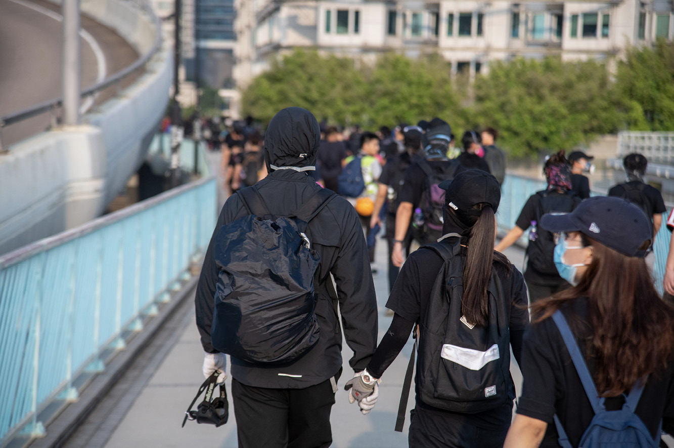 A young man and woman hold hands as they avoid Hong Kong Police and depart from - photo 11