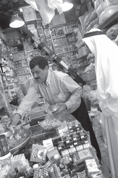 A man looks on as a vendor weighs out some grain in downtown Kuwait city - photo 23