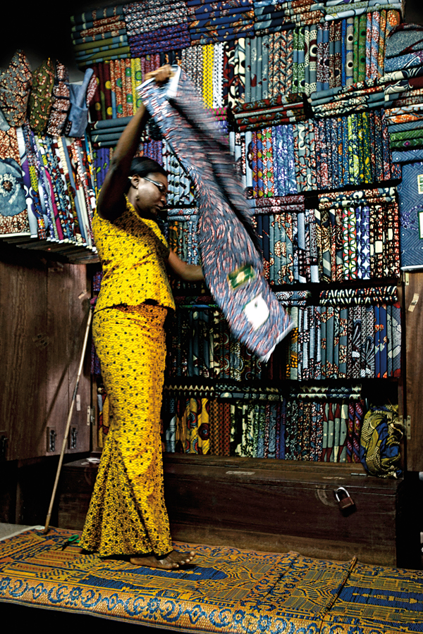 Togolese cloth trader at her market stand handling a classic pattern called - photo 2