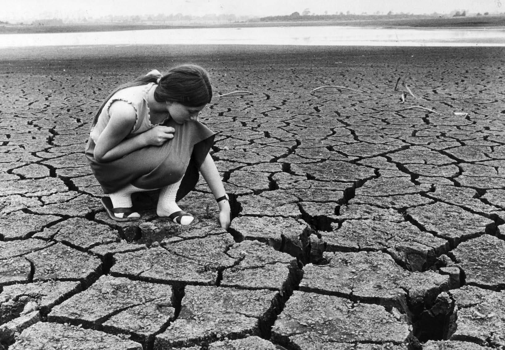 A young local girl slips her hand between the wide cracks in the dried-up - photo 4