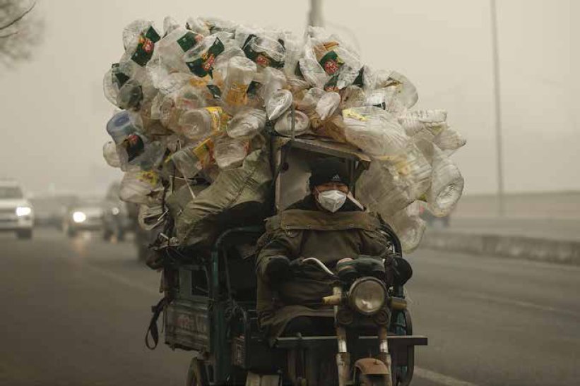 A man rides riding a tricycle with plastic bottles to be recycled on a day of - photo 2