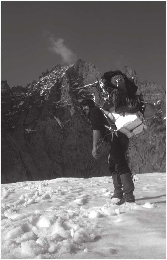 The author carrying gear up to base camp below the unclimbed south face of - photo 1