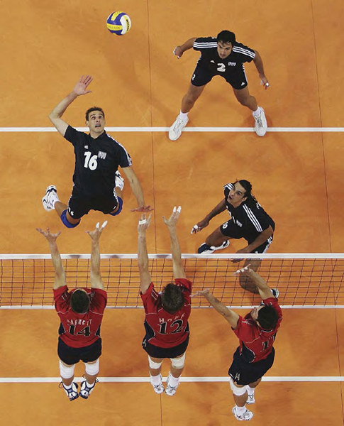 A member of Greeces volleyball team spikes the ball against the US team - photo 8