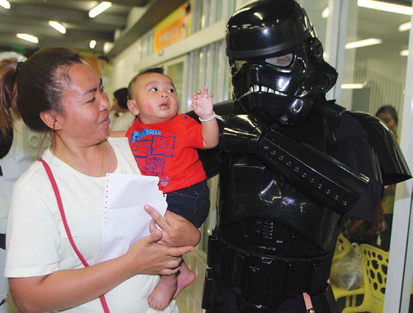 This community service volunteer in Star Wars gear is visiting with a young - photo 4