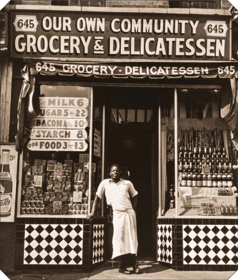 An African-American store owner stands in the doorway of his Harlem grocery - photo 7