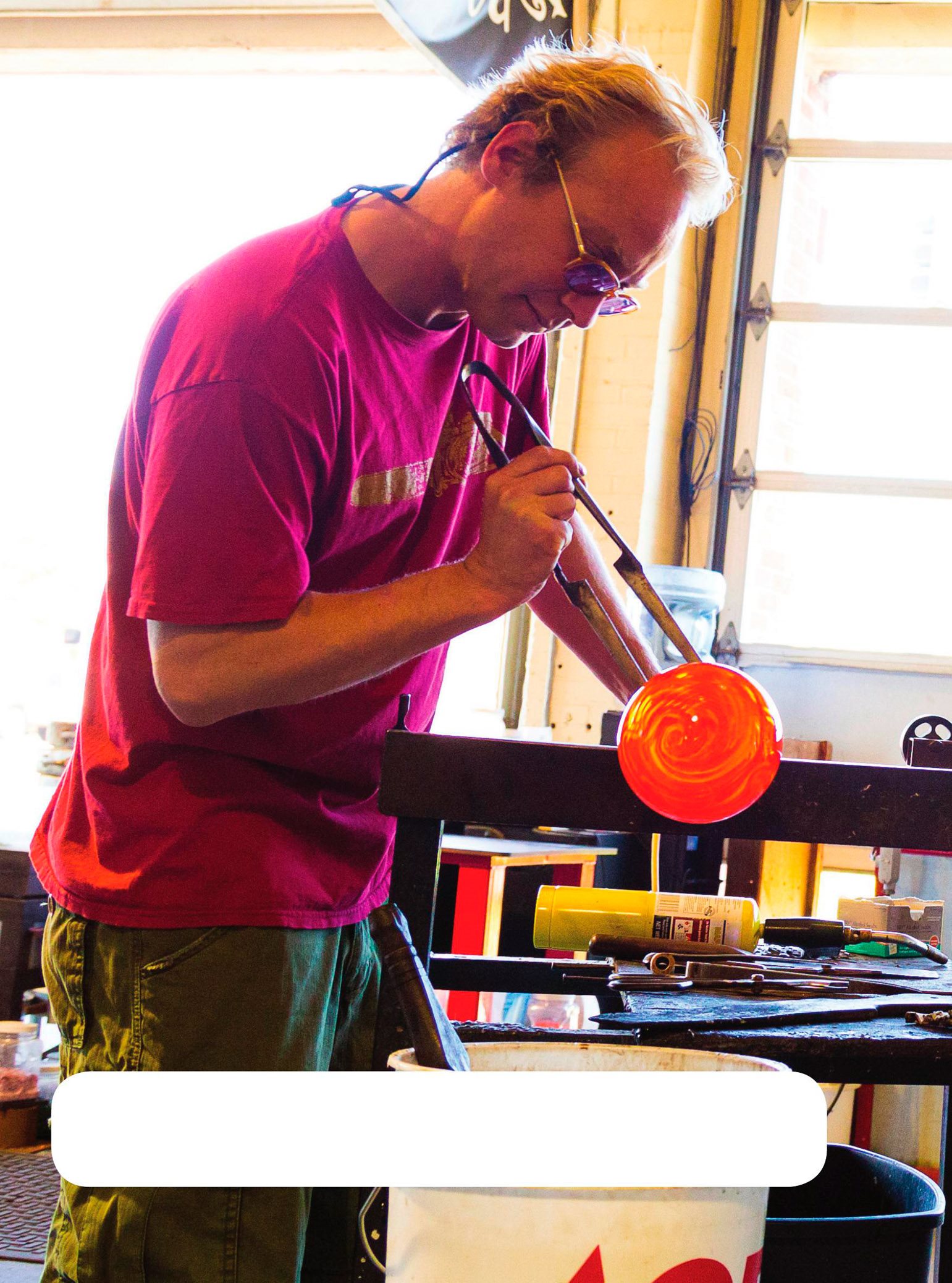 A glassblower blows through a tube into hot glass to make shapes The - photo 10