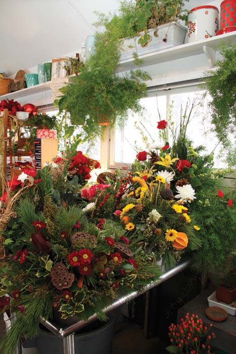 Counters laden with a variety of floral arrangements awaiting delivery to the - photo 6