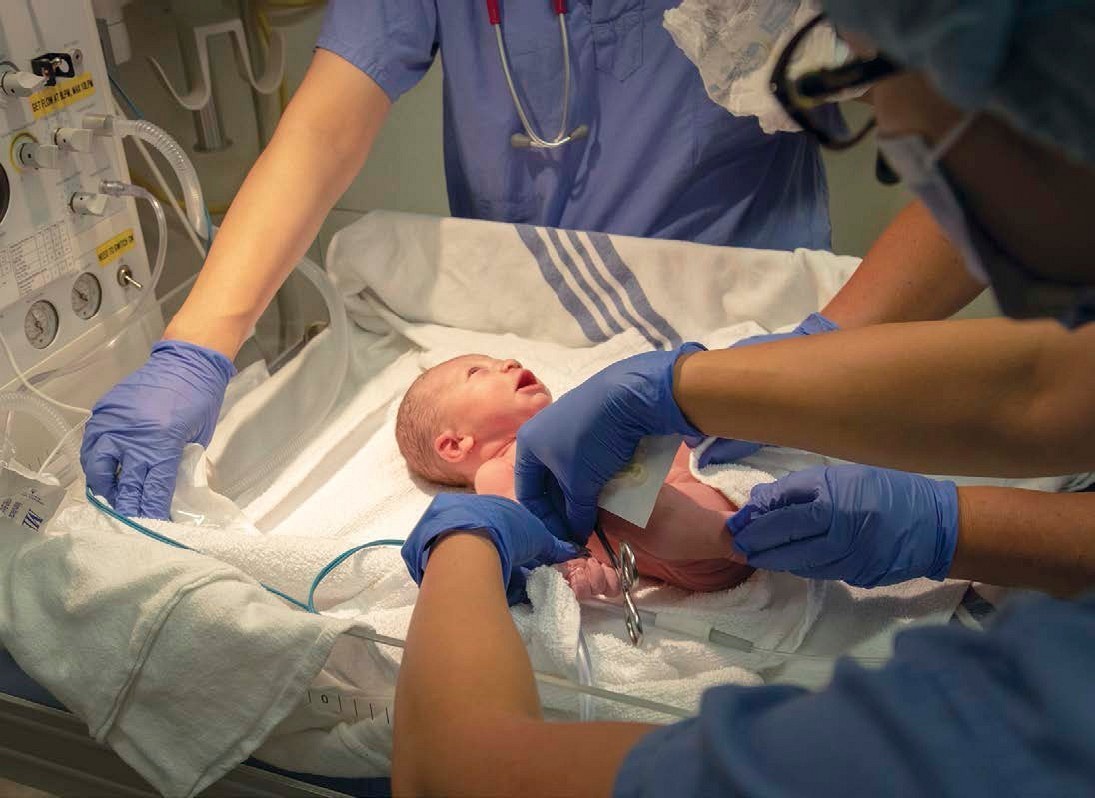 Medical personnel attend to a newborn child by cutting the umbilical cord and - photo 2