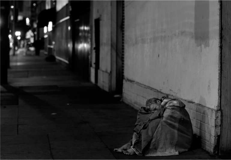 A man sits quietly on a sidewalk in the Skid Row neighborhood of Los Angeles - photo 4