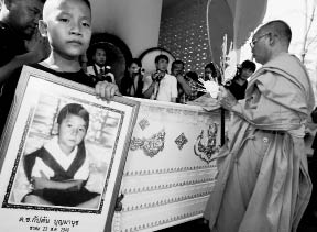 Kaptans brother holds a framed photo of Kaptan Boonmanuch at his funeral - photo 3