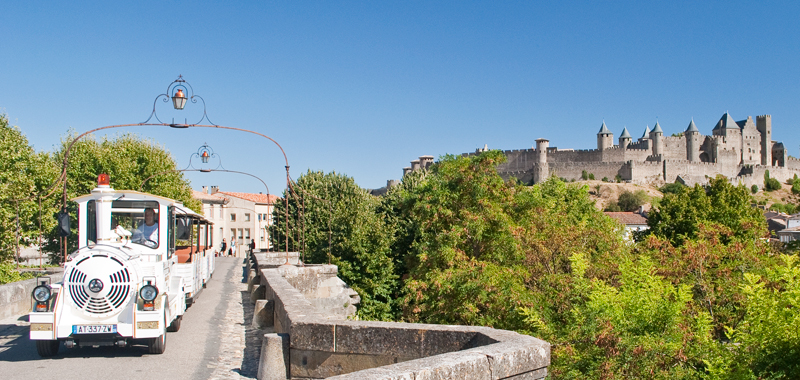 The petit train crossing a bridge with the imposing ramparts of the medieval - photo 7