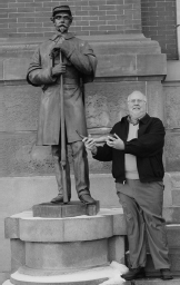 Sam Crompton holding a powder horn poses by the Soldiers Memorial in - photo 2