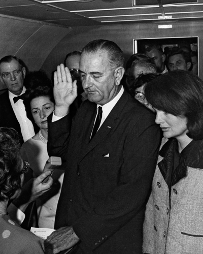 Jacqueline Kennedy right and Lady Bird Johnson stand by Lyndon B Johnson as - photo 5