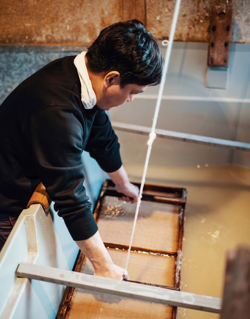 A man makes paper using traditional methods separating pulp and fiber from - photo 5