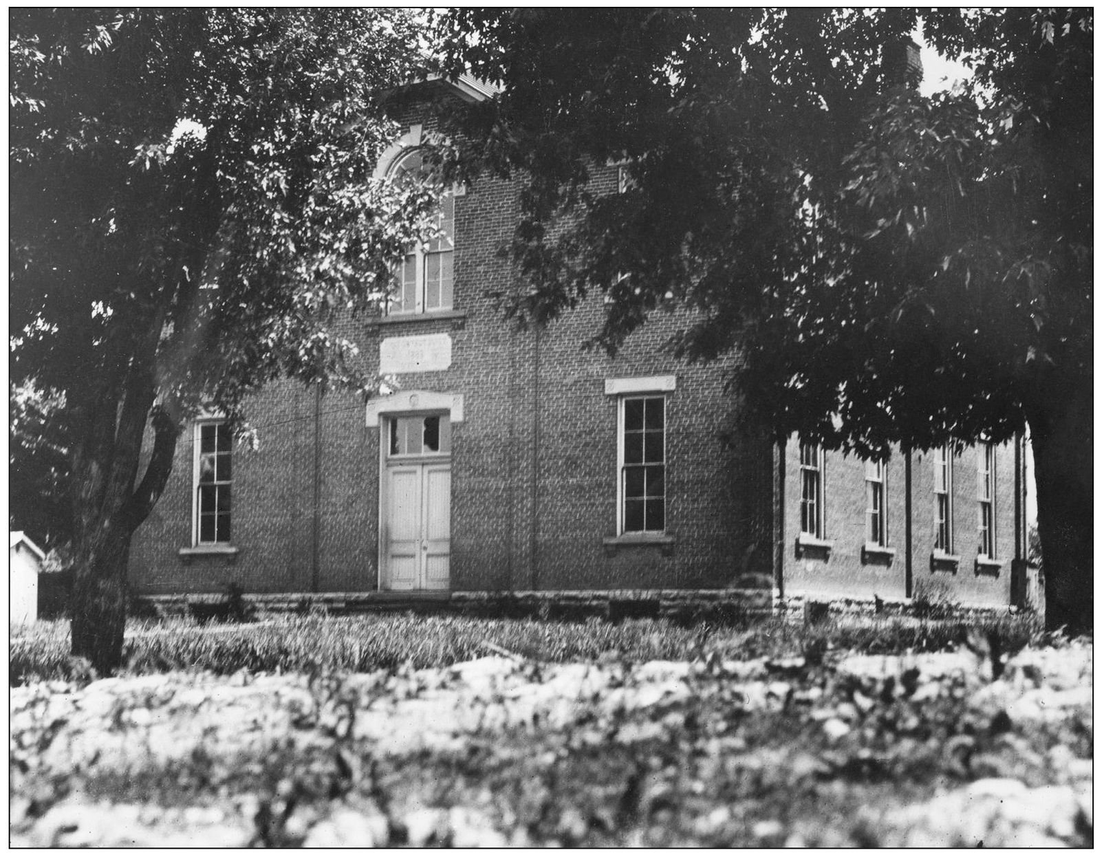 The Falmouth High School building shaded by large trees stands abandoned at - photo 4