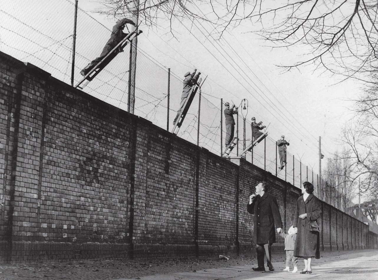 A East Berlin border guards add barbed wire to the newly built wall in - photo 7