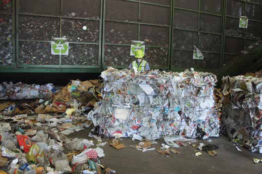 A bale of sorted paper in front of cages that hold sorted tin cans juice - photo 9