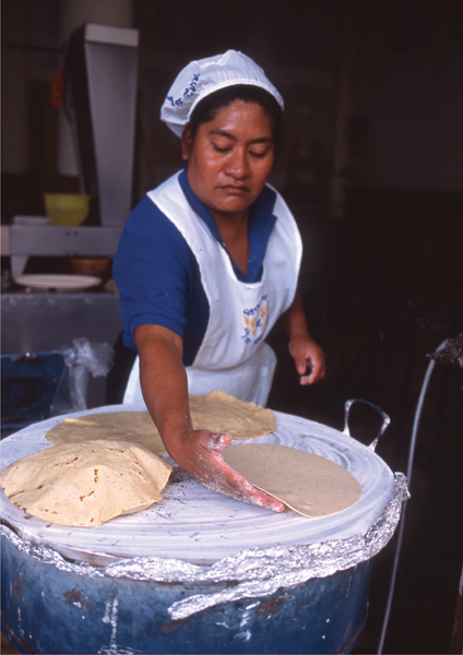 In a market fonda a cook deftly lays tortillas on a clay comal before flipping - photo 14