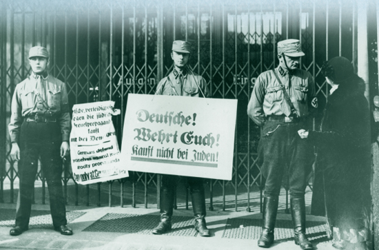 Nazi troops hold anti-Semitic placards in front of a locked storefront during a - photo 4