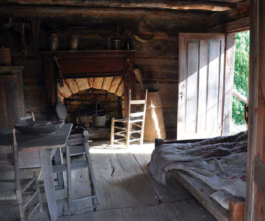 An open door admits sunlight to a cabins main room A rope bed takes up one - photo 5