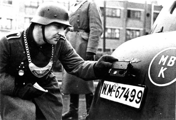 A Feldgendarmerie Unteroffizier carrying out a check on the rear lights of a - photo 4