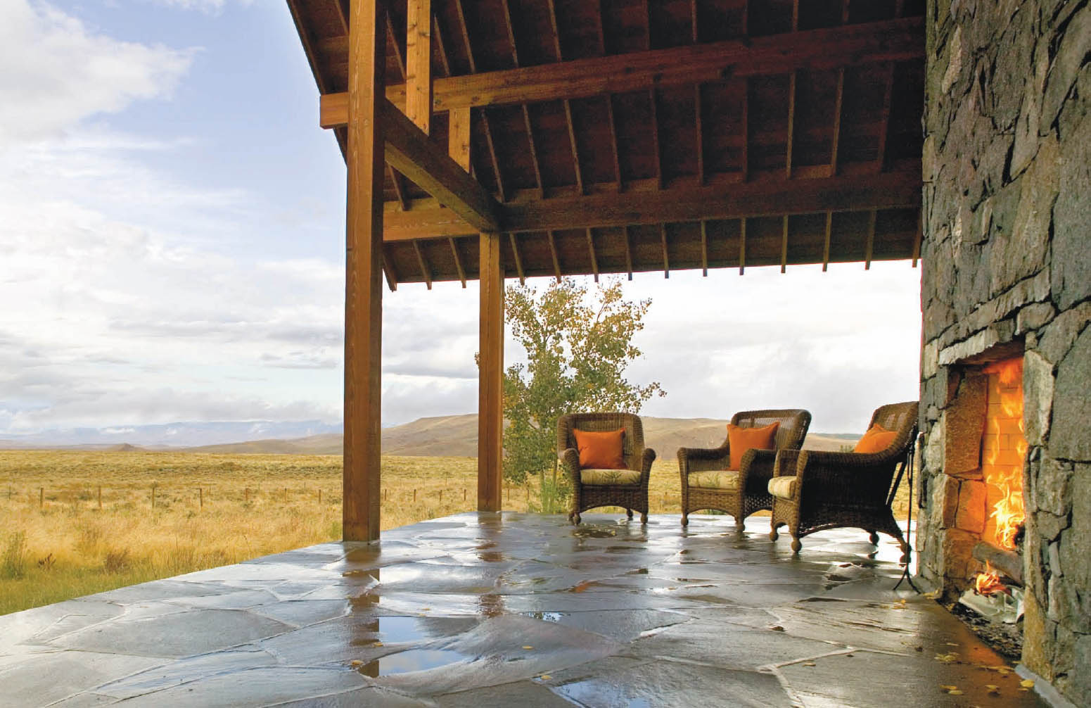 A large porch with a double-sided stone fireplace and exposed roof rafters - photo 12